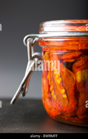 Ein Glas gefüllt mit Sun-Dried Tomaten und Olivenöl auf einem schwarzen Hintergrund. Stockfoto