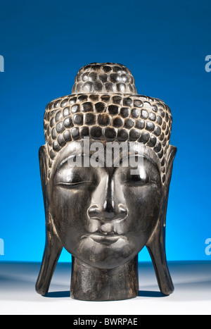 A Kopf des Buddha aus Süd-Ost-Asien, Indochina vor einem blauen Hintergrund aus Holz geschnitzt Stockfoto