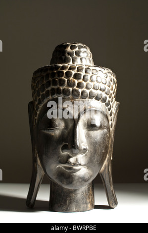 A Kopf des Buddha aus Süd-Ost-Asien, Indochina vor einem dunklen Hintergrund aus Holz geschnitzt Stockfoto