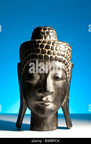 A Kopf des Buddha aus Süd-Ost-Asien, Indochina vor einem blauen Hintergrund aus Holz geschnitzt Stockfoto