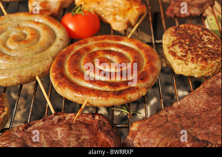 Spirale Cumberland Würstchen und Rindersteak gegrillt auf einem Holzkohlegrill im Freien. Stockfoto