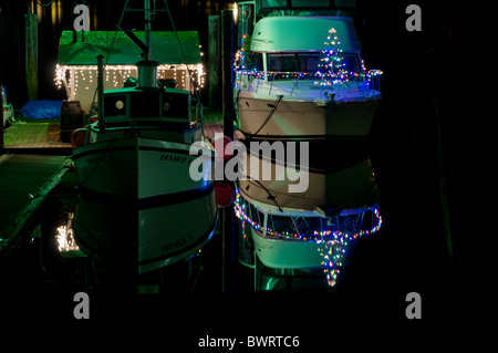 Helle Weihnachtsbeleuchtung Leuchten auf dieses Boot und seine Reflexion über die Puget Sound Bucht auf eine Stille und ruhige Nacht. Stockfoto