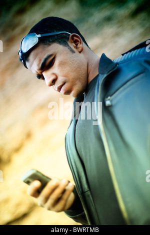 Ein junger afrikanischer Mann Blick auf sein Handy. Konzentrieren Sie sich auf den konzentrierten Gesichtsausdruck. Flach-Abteilung des Feldes. Kopieren Sie Raum. Stockfoto