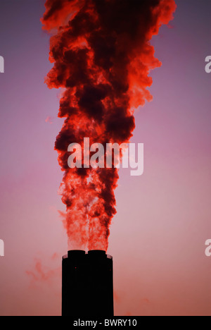 Rauchen Sie, gießt aus einem Kraftwerk Schornstein mit einem roten Sonnenuntergang Silhouette, Widnes, Cheshire, England, UK Stockfoto