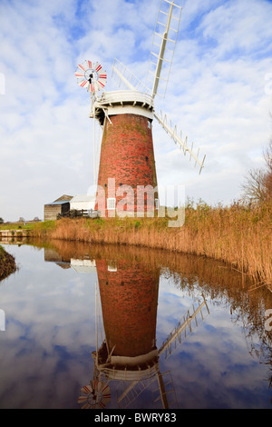 Horsey Windmühle Windpumpe spiegelt sich in einem Deich Wasserlauf, gesäumt von Schilf in Norfolk Broads. Horsey Norfolk England UK Großbritannien Stockfoto