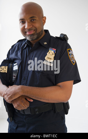 Lächelnd afroamerikanischen Polizisten halten Kappe Stockfoto