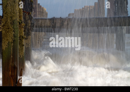 Wasser-Streams aus verlassenen Meer Verteidigung auf Happisburgh Strand, nachdem eine Welle über sie abgestürzt. Stockfoto