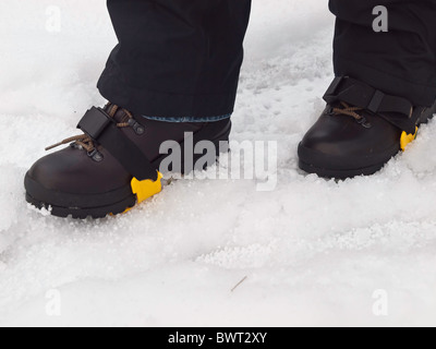 Frau die Füße in eine Wanderschuhe mit Steigeisen ausgerüstet für Sicherheit auf Schnee und Glatteis Stockfoto