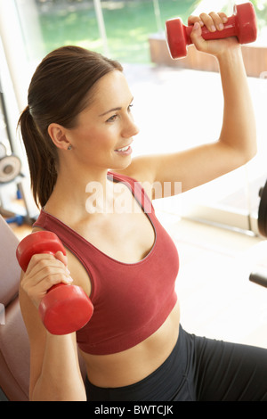 Junge Frau, die Arbeit mit Gewichten im Fitnessstudio Stockfoto