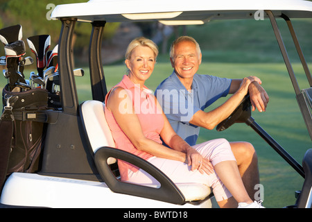 Älteres Paar Reiten In Golfwagen auf Golfplatz Stockfoto