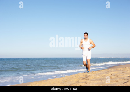 Junger Mann In Fitnesskleidung Strand entlang laufen Stockfoto