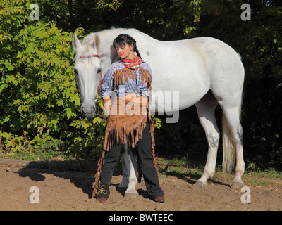 Hübsches Mädchen im indianischen Anzug posiert mit weißen Pferd Stockfoto