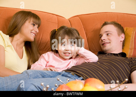 Glückliche Eltern sahen einander mit ihrer Tochter zwischen ihnen und sprechen Stockfoto