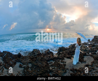 Junge Frau mit Regenschirm stehen auf Felsen in der Nähe von Meer Stockfoto