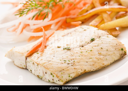 Barramundi Filet mit Karotten, Rettich und Chips als Closeup auf einem weißen Teller Stockfoto