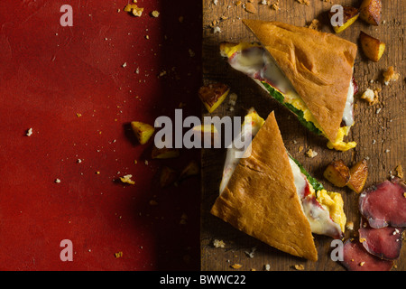 Ein heißes Panino mit Focaccia, Wild Speck, Arugola, Rührei und Käse, eine rustikale Holz Schneidebrett getroffen, zubereitet am Stockfoto