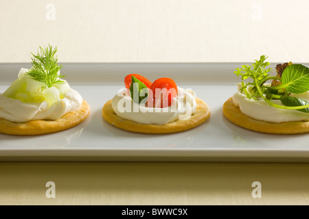 Kekse mit cremiger Käse verbreiten, garniert mit Tomaten, Basilikum, Gurken, Dill, gemischte grün und Radieschen oben auf einem weiß r Stockfoto