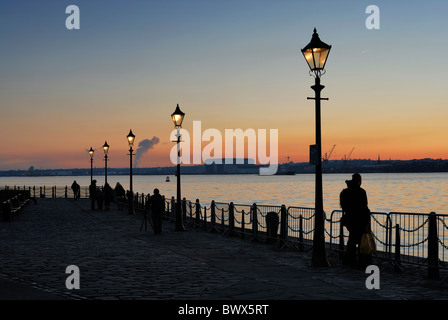 Menschen genießen den Sonnenuntergang über den Fluss Mersey an der Liverpool-Promenade am Albert Dock. Stockfoto