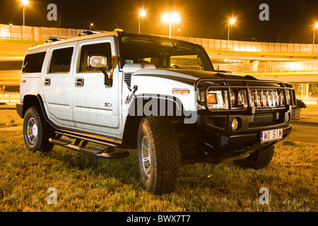 Silber-Hummer H2 4WD SUV Allradfahrzeug, eine Abendstimmung, beleuchtete Autobahn im Hintergrund Stockfoto