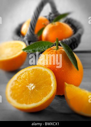Frische Orangen ganze und geschnittene Hälften mit Blättern in einer Küche-Einstellung