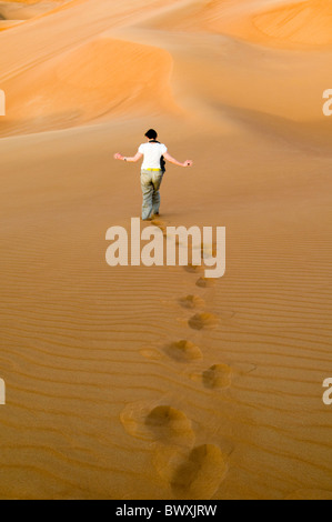 Frau mit ausgestreckten Armen auf einer Sanddüne in der Wüste in Dubai, Vereinigte Arabische Emirate Stockfoto