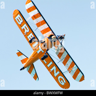 Single Breitling Boeing Stearman Doppeldecker in Eastbourne Airbourne Air Display mit einer Wingwalker auf obere Tragfläche - Flugzeug-Banking-Seite Stockfoto