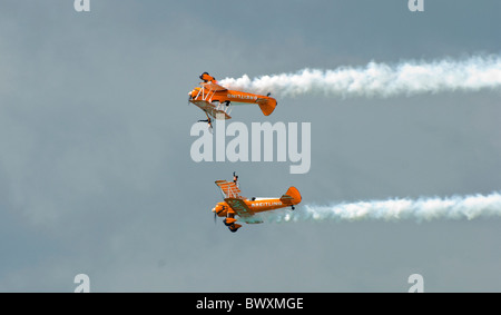 Zwei Paar von Breitling Boeing Stearman Doppeldecker in Eastbourne Airbourne Air Display mit einem Wingwalker auf jedem invertiert ein Flugzeug Stockfoto