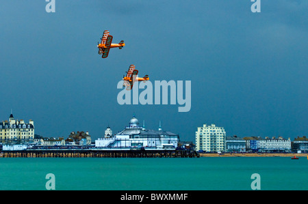 Zwei Paar von Breitling Boeing Stearman Doppeldecker in Eastbourne Airbourne Air Display mit einem Wingwalkers fliegen vorbei Pier-Gebäude Stockfoto