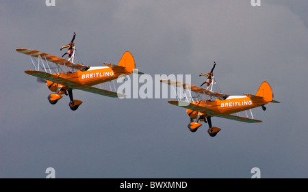 Zwei Paar von Breitling Boeing Stearman Doppeldecker in Eastbourne Airbourne Air Display mit einem Wingwalkers tun Kopf steht invertiert Stockfoto