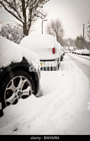 Verschneite Autos auf der Straße Stockfoto