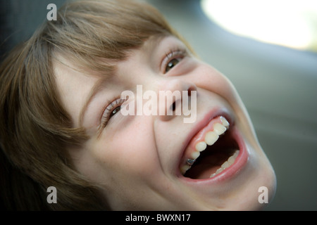 Acht Jahre altes Kind Lachen im Fenster Licht, schließen sich Stockfoto