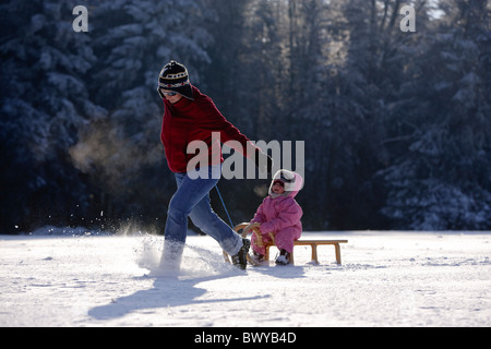 Frau Kleinkind Mädchen auf Holzschlitten in Winterlandschaft, Dobel, Schwarzwald, Gerrmany ziehen Stockfoto