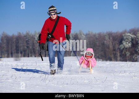 Frau Kleinkind Mädchen auf Holzschlitten in Winterlandschaft, Dobel, Schwarzwald, Gerrmany ziehen Stockfoto