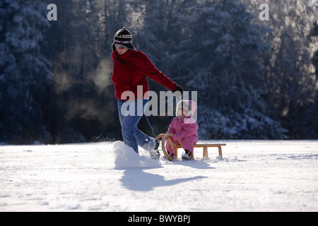 Frau Kleinkind Mädchen auf Holzschlitten in Winterlandschaft, Dobel, Schwarzwald, Gerrmany ziehen Stockfoto