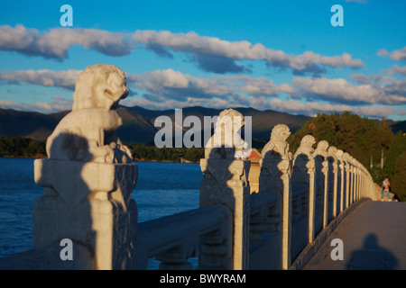 Stein geschnitzten Löwen auf die siebzehn-Bogen-Brücke im Sonnenuntergang, Sommerpalast, Peking, China Stockfoto