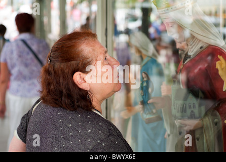 Eine Frau, die an einem Schaufenster eines Ladens, Verkauf von Devotionalien, Czestochowa, Polen Stockfoto