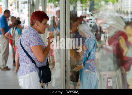 Eine Frau, die an einem Schaufenster eines Ladens, Verkauf von Devotionalien, Czestochowa, Polen Stockfoto