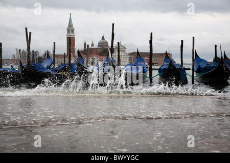 Wasser spritzt auf der Piazetta San Marco an den hohen Gezeiten. San Giorgio Maggiore ist im Hintergrund über den Markusplatz Becken Stockfoto