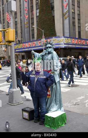 Performance-Künstler wie die Statue of Liberty interagiert mit Touristen, etwas Geld im Urlaub von Radio City, New York Stockfoto