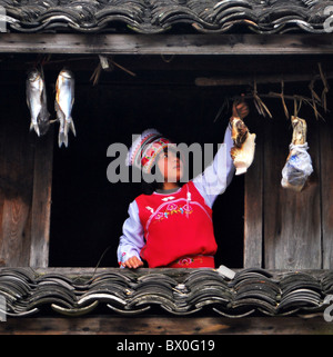 Junge Frau Bai ethnisch aufhängen Perserved Fleisch, Waipokeng Dorf, Xinchang, Zhejiang Province, China Stockfoto