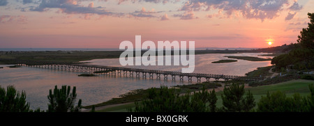 Portugal, Algarve, Sonnenuntergang über der Lagune und die hölzerne Brücke zum Strand von Quinta do Lago Stockfoto