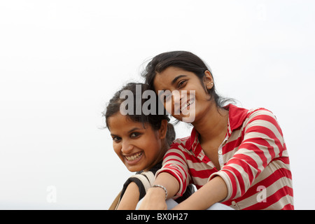 Zwei junge indische weibliche Erwachsene sitzen gemeinsam Lächeln Stockfoto