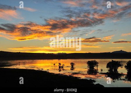 Blauer Himmel orange Wolken reflektiert in den Gewässern von Bahia Redonda, mit Sonnenuntergang Silhouette Andengipfel, El Calafate in Patagonien Stockfoto