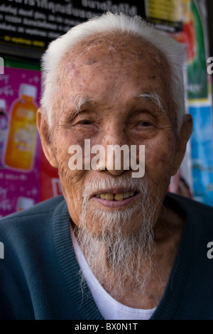 Ein alter asiatischer Mann mit weißen Haaren und einem langen Ziegenbart lächelt in Mae Hong Son, Thailand. Stockfoto