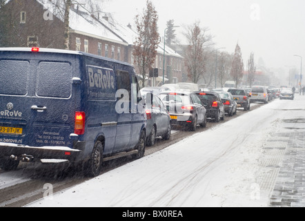 Verkehr, der langsam seinen Weg auf einer verschneiten Straße in den Niederlanden Stockfoto