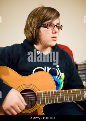 Ein junges Mädchen, das Tragen der Brille eine 12-saitige Akustikgitarre zu spielen. Stockfoto