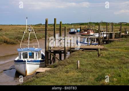 Hölzerne Fischerboote vertäut in einem Kanal bei Ebbe an der Küste von Norfolk Stockfoto