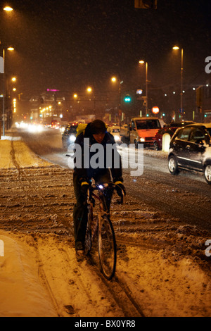 Mann Reiten Fahrrad auf der Straße im Schnee Stockfoto