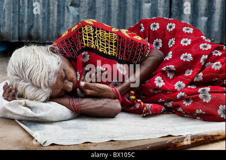 Alte indische obdachlose Frau schläft auf der Straße. Andhra Pradesh, Indien Stockfoto