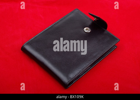 Schwarze Leder-Portemonnaie isoliert auf rotem Hintergrund. Studio gedreht. Stockfoto